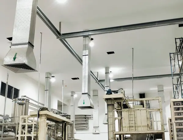 Ruang produksi putih dengan ducting galvanis yang turun ke difuser